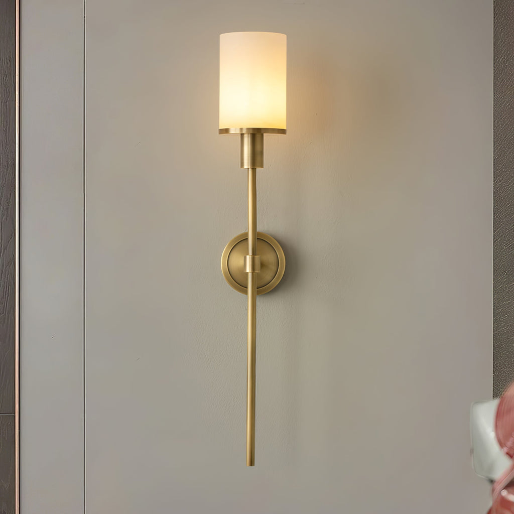 Clérachic brass alabaster sconce lit on a grey wall panel between dark timber uprights
