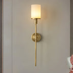Clérachic brass alabaster sconce lit on a grey wall panel between dark timber uprights
