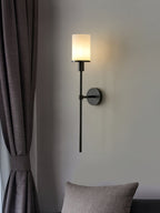 Clérachic black alabaster sconce lit beside a grey curtain and a textured cushion in a quiet corner