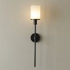 Clérachic black alabaster wall sconce lit straight on, the opal shade bright against a plaster wall