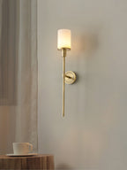 Clérachic brass alabaster sconce lit next to a sheer curtain, above a wooden stump table set with a cup