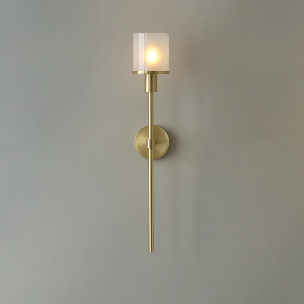 Clérachic brass alabaster wall sconce against a cool grey wall, the fluted shade glowing softly around the bulb
