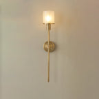 Clérachic brass Nordic alabaster wall sconce lit on a warm beige wall, clear outer glass layering the shade