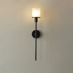 Clérachic black-finish version of the alabaster wall sconce, lit, its dark stem set against a warm cream wall