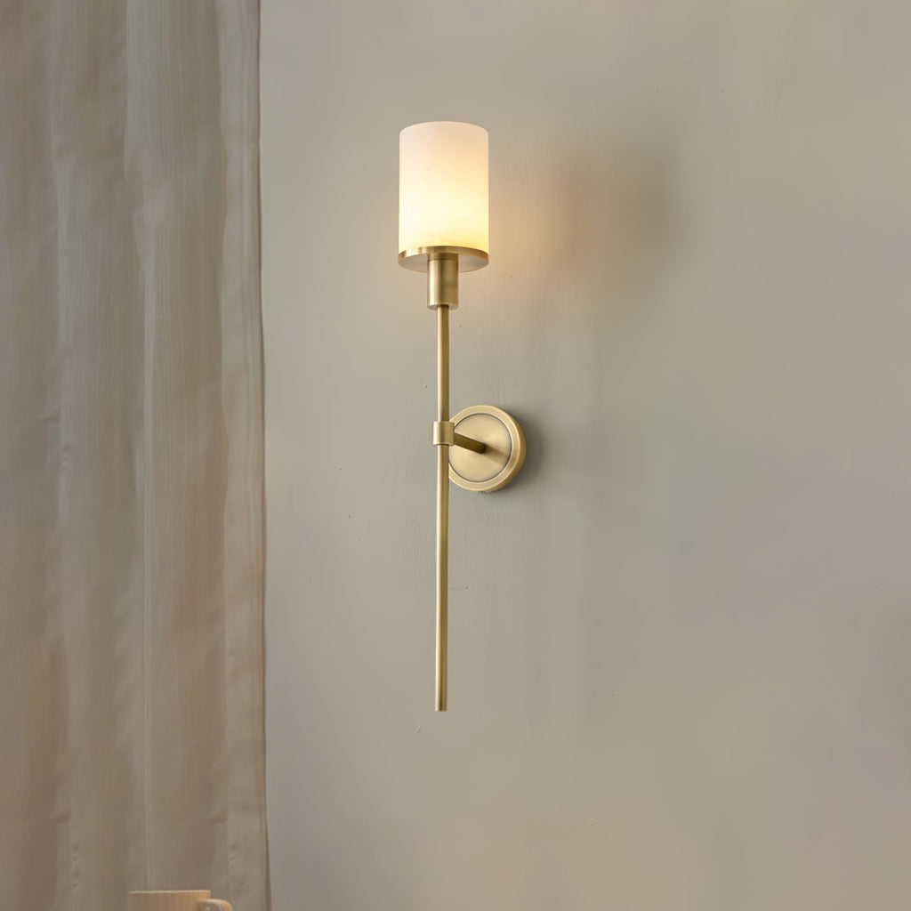 Clérachic brass alabaster sconce lit beside a sheer curtain, seen at an angle against a plain wall