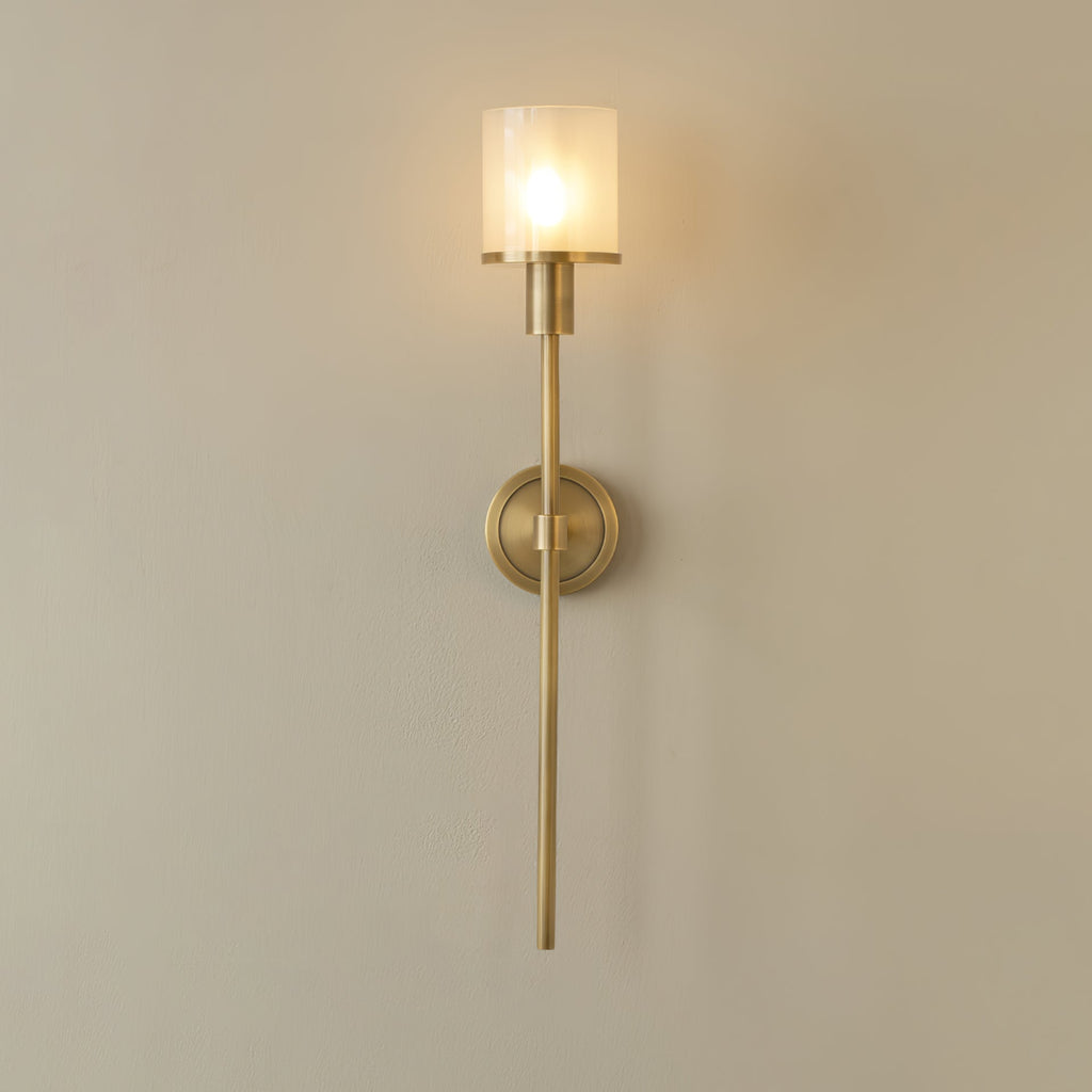 Clérachic brass alabaster sconce with a clear glass outer sleeve over the frosted inner shade, lit