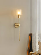 Clérachic brass alabaster sconce lit in a studio corner, the marbled shade catching light near a leaning frame