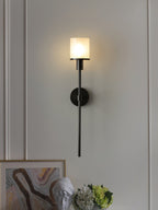 Clérachic black alabaster sconce lit on a white panelled wall above framed art and a plaster bust