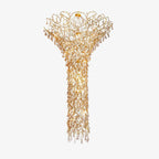 The same chandelier lit, its warm glow running the full drop from the branching crown down to the narrow tail.