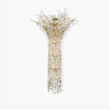 Brass branch chandelier on a white background, clear crystal drops falling from the spreading crown into a long column.