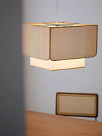 Close angle on this Clérachic pendant's rattan lattice weave, glowing above a wood bench with a woven panel.