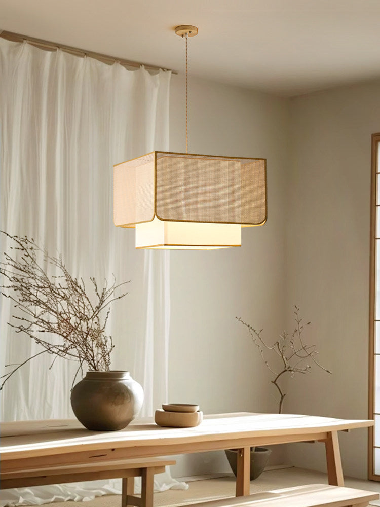 Beside sheer curtains and a wood bench holding pottery, this Clérachic pendant's rattan box shade glows warm.