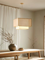 Beside sheer curtains and a wood bench holding pottery, this Clérachic pendant's rattan box shade glows warm.