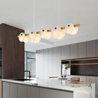 The brass version lit over a white kitchen island, seen at an angle from across the room.