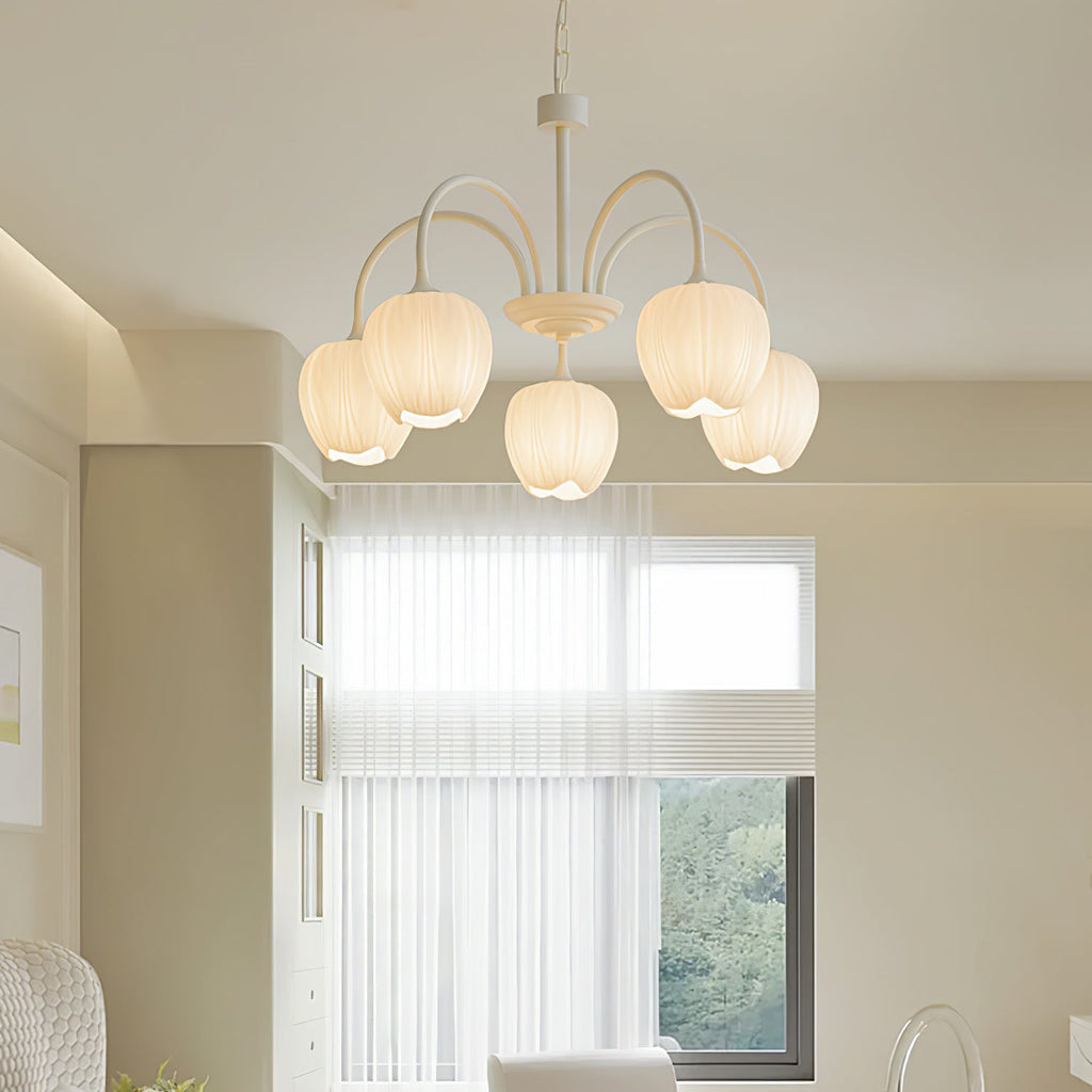 White glass tulip chandelier lit warm above a room