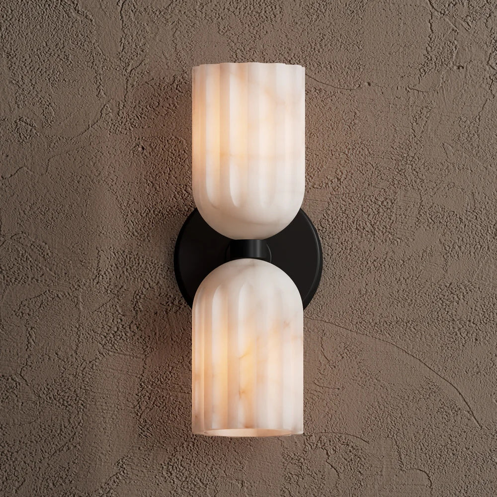 Black-finish sconce with veined alabaster shades casting warm light upward and downward