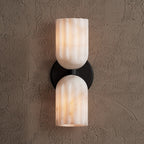 Black-finish sconce with veined alabaster shades casting warm light upward and downward
