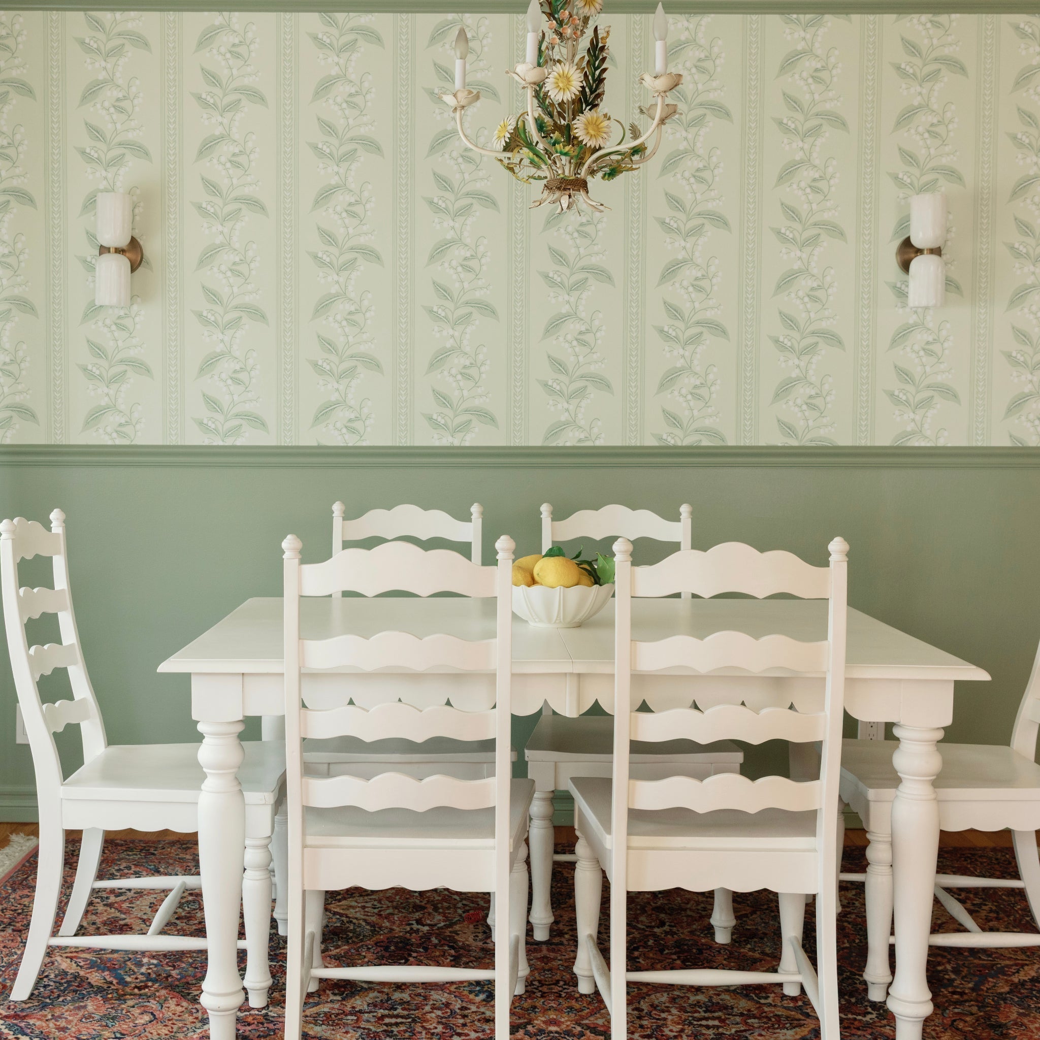 A pair of the alabaster sconces flanking a green wallpapered dining room wall above a white table