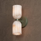 Close-up of the sage green sconce, showing the fluted alabaster shades and their amber veining