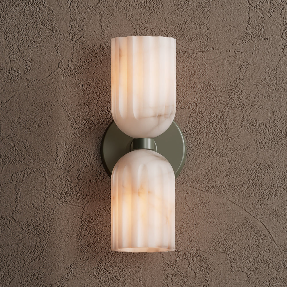 Double alabaster wall sconce in sage green, lit and shown head-on against a textured taupe plaster wall