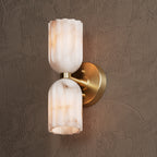 Brushed brass sconce at an angle, showing the disc backplate and the arm joining both shades