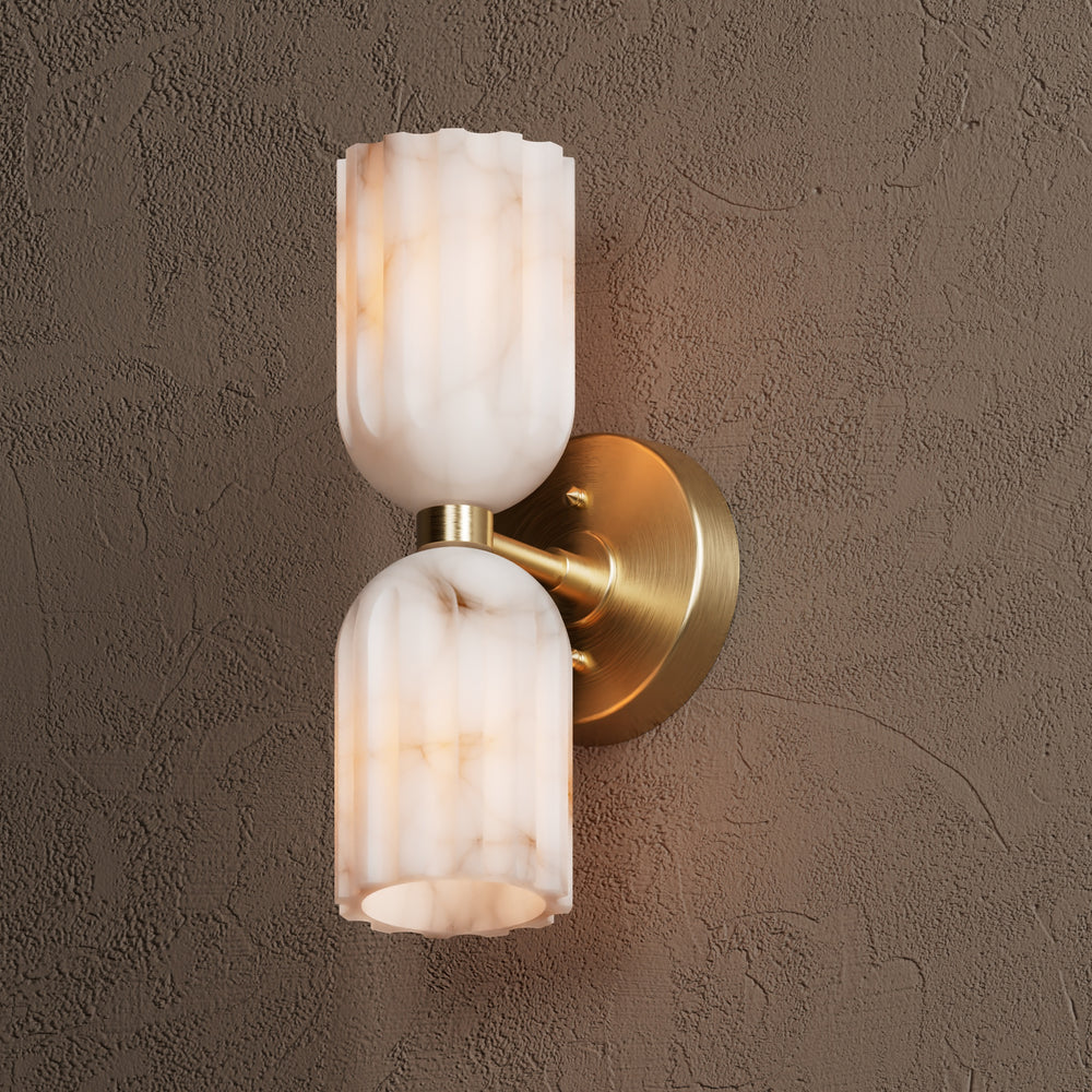 Brushed brass sconce at an angle, showing the disc backplate and the arm joining both shades