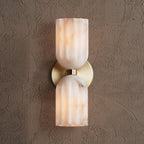 Front view of the brass sconce showing the round backplate set between two alabaster shades