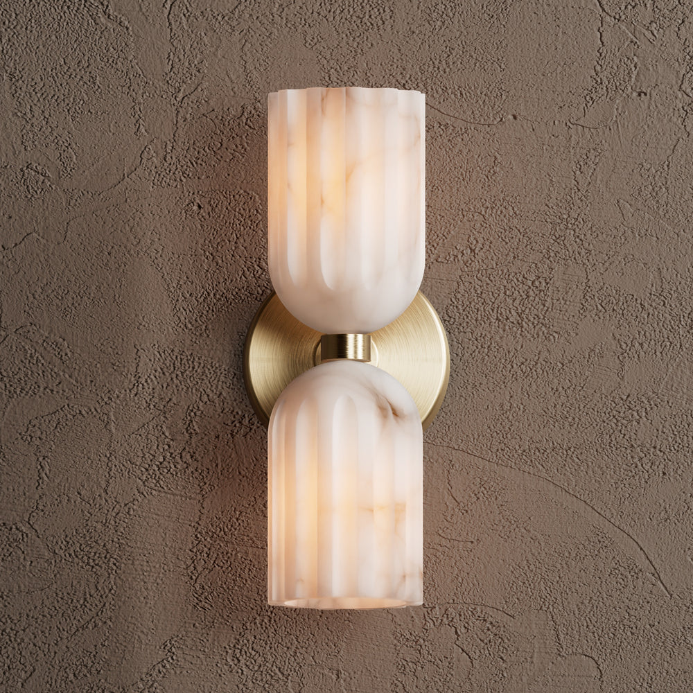 Brushed brass double wall sconce with alabaster shades, lit and photographed straight on