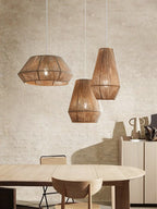 In a plaster-walled dining room, three jute rope Clérachic pendants hang above a round wood table.