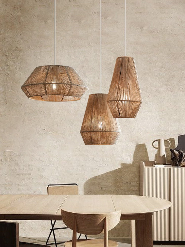 In a plaster-walled dining room, three jute rope Clérachic pendants hang above a round wood table.