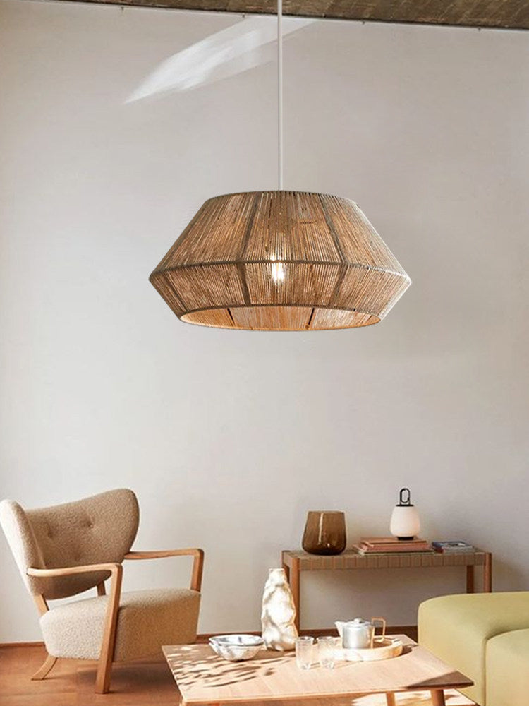 A single bowl-cone Clérachic pendant glows above a living room with a wood armchair and low side table.