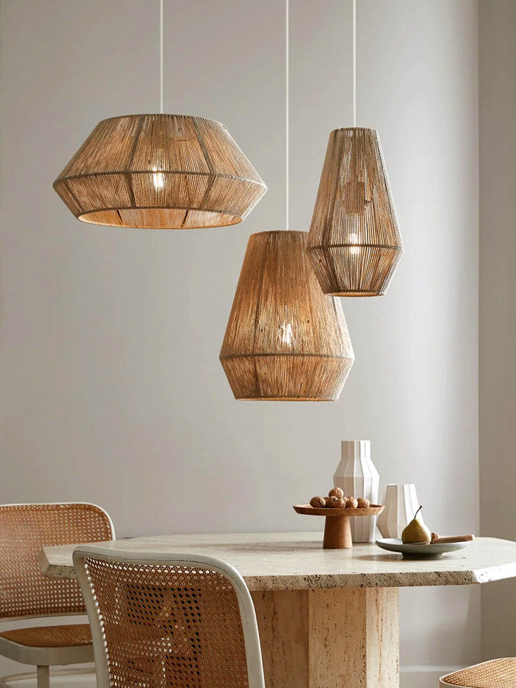 Above a travertine-topped table set with a bowl of pears, three jute rope Clérachic pendants hang together.