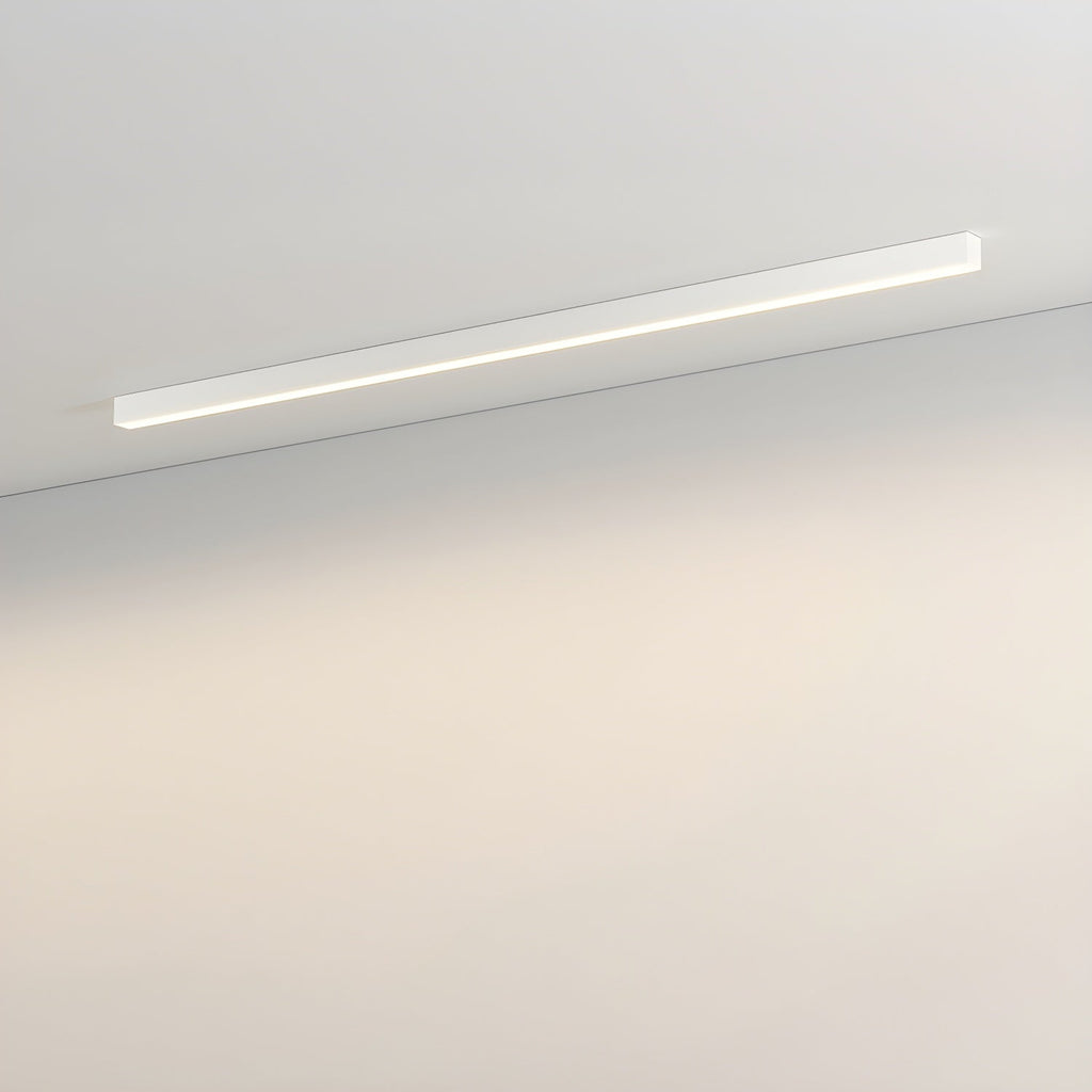This Clérachic ceiling light in white runs along a plain wall, its diffuser glowing with a warm light.