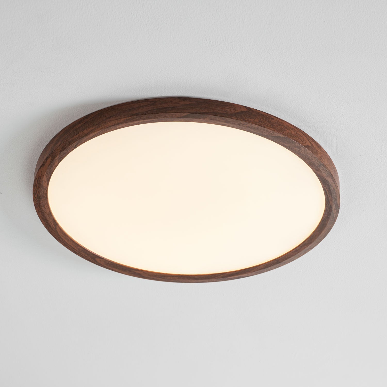 Round ceiling light with wood-grain edge lighting a hallway