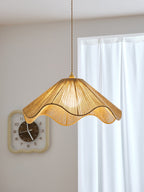 Beside a round wall clock and a sheer curtain, this lit Clérachic pendant's wavy hemp-rope hem glows warm.
