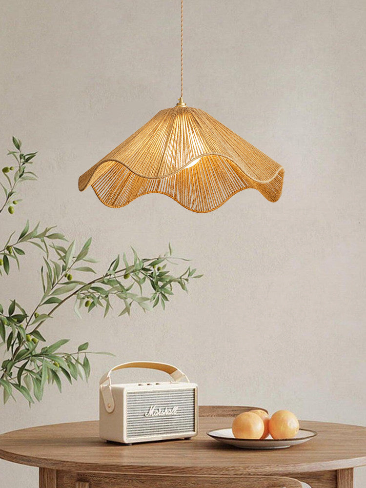 A cream radio and a bowl of peaches sit on the table below this lit Clérachic pendant, glowing warm.