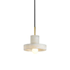 Ritta alabaster pendant light with hat-shaped shade, lit globe bulb below the brim, on white.