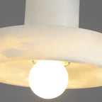 Close-up beneath the brim, showing the translucent alabaster glowing around the globe bulb.
