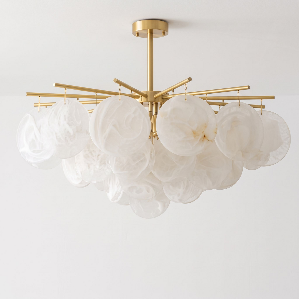 Filling the frame on a plain white background, this brass Clérachic chandelier's alabaster discs cluster into one dense mass.