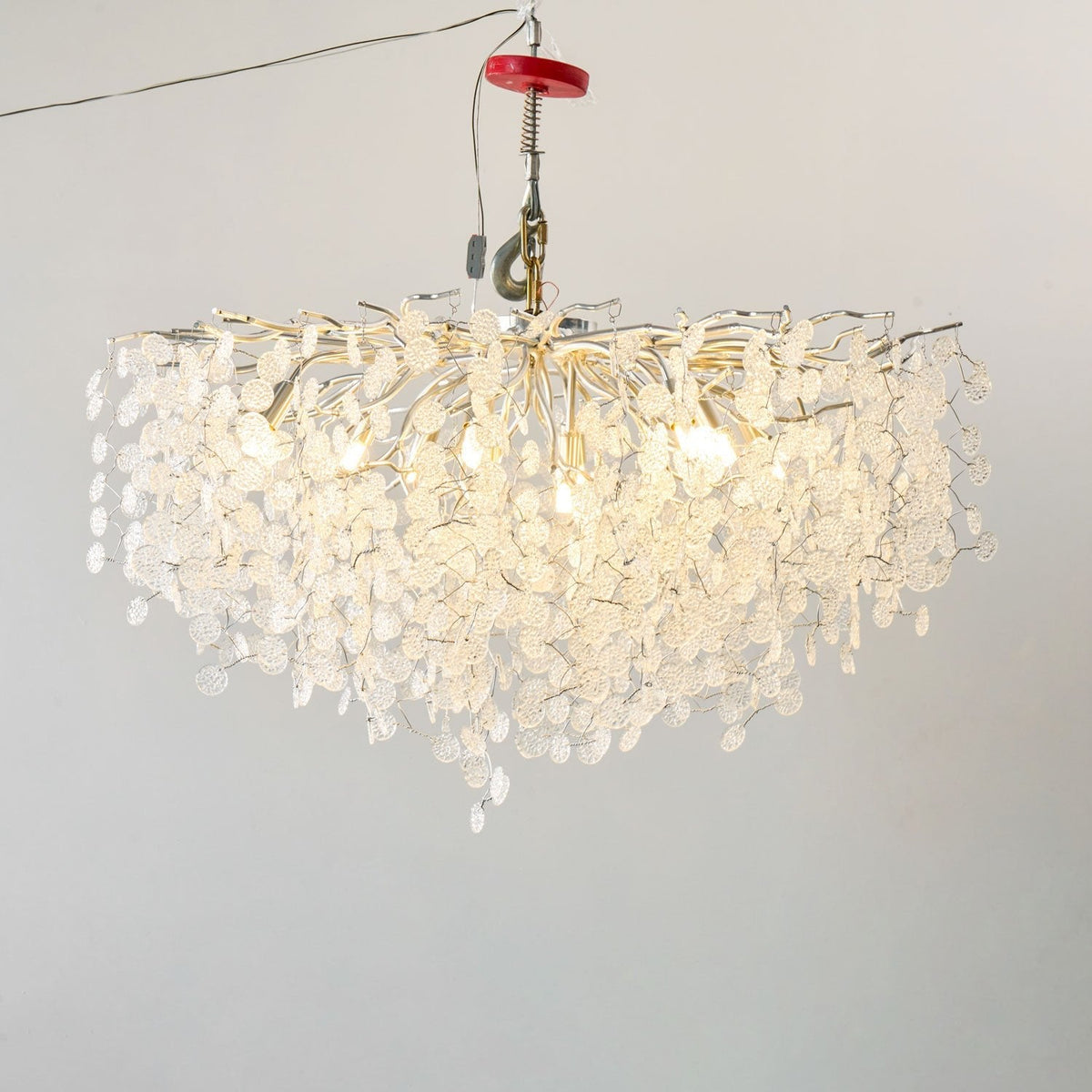 Lit against a plain grey backdrop, this Clérachic ceiling light in silver glows through its clear glass discs, hung from a test rig.