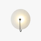 The Kristy wall lamp in black on a plain white background, showing the full round disc and slim hooked arm.