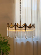 Copper chandelier with clear glass shades glowing against a dark wall