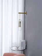 Brass-finish glass wall lamp shown against a soft backdrop