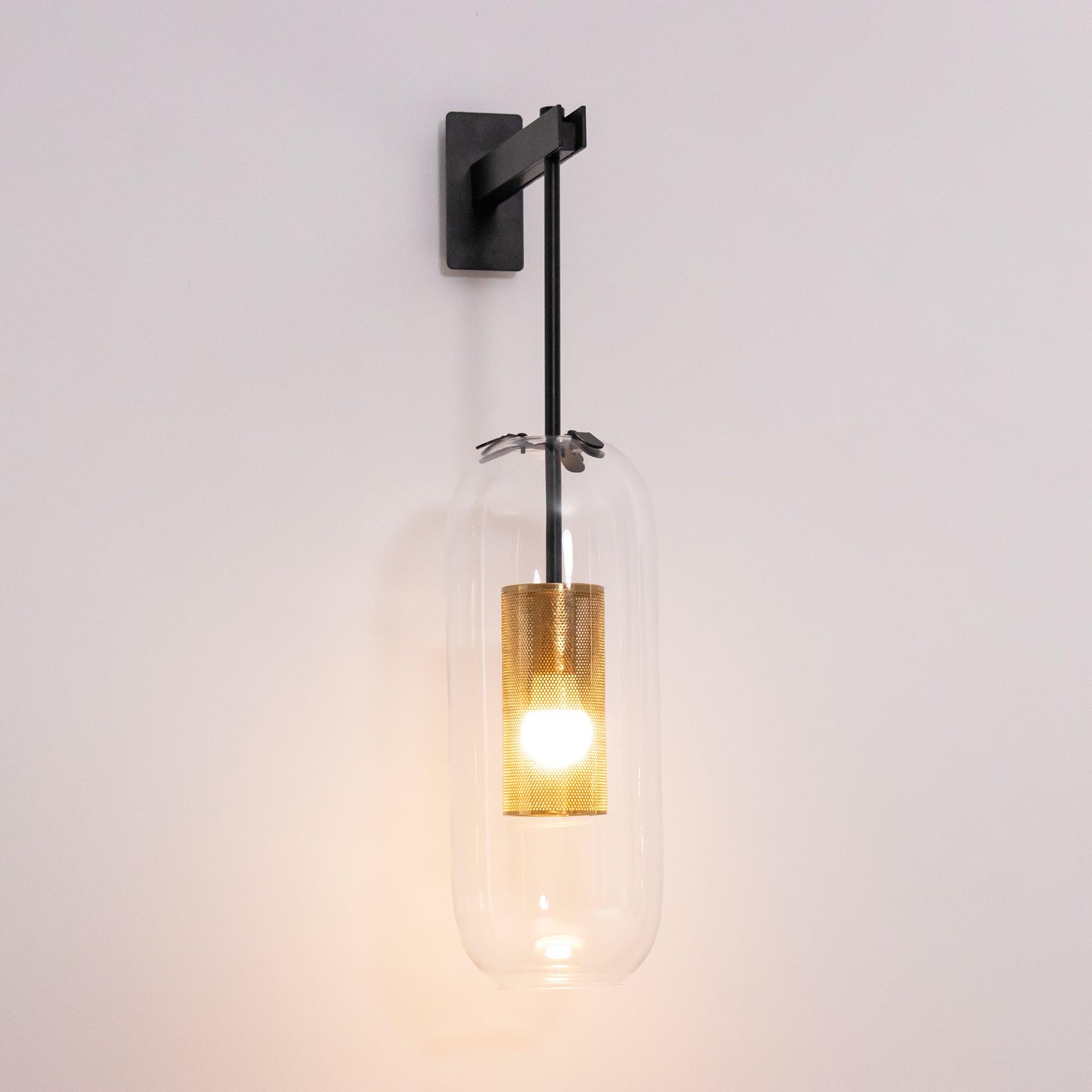 Glass wall lamp with slim arm illuminated against a neutral wall
