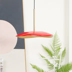 Pendant light with clean disc shade shown against a wall