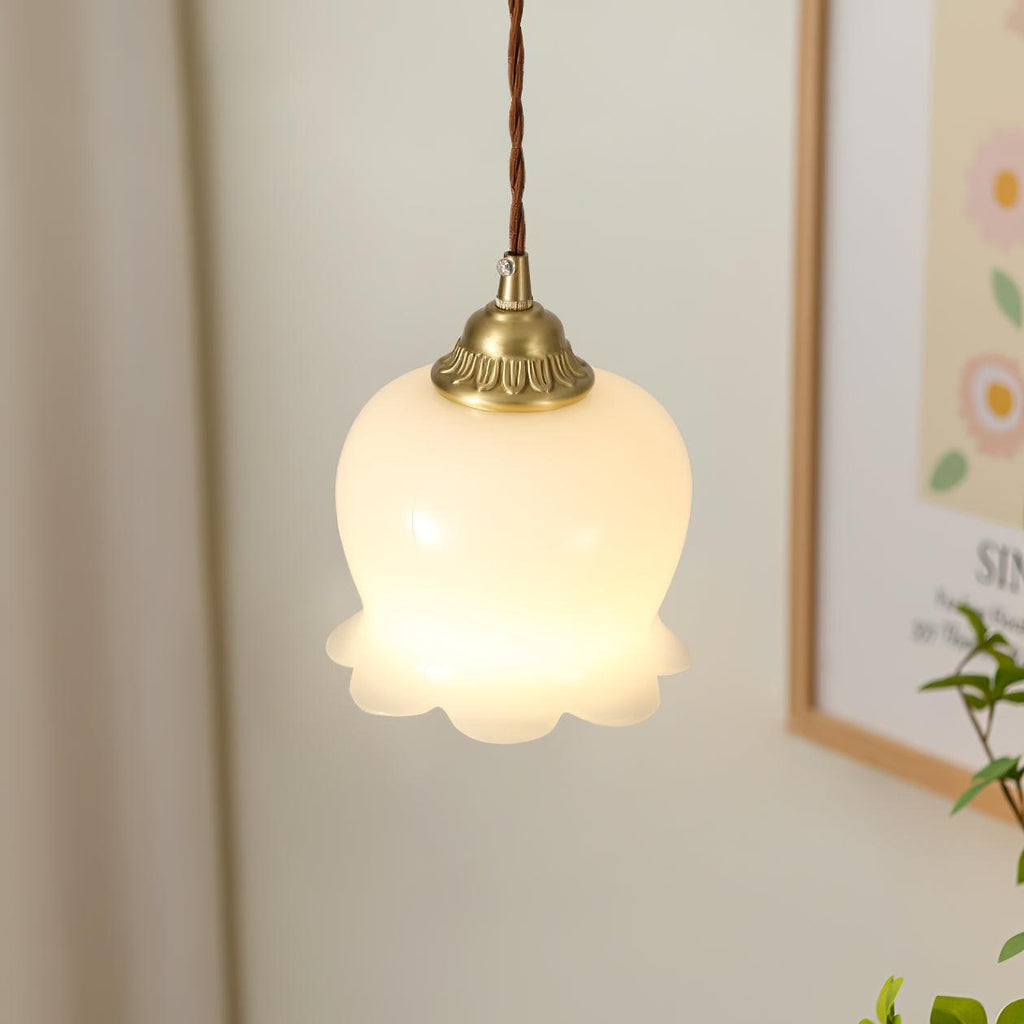Brass petal pendant light shown close up against a wall
