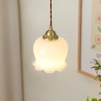 Brass petal pendant light shown close up against a wall