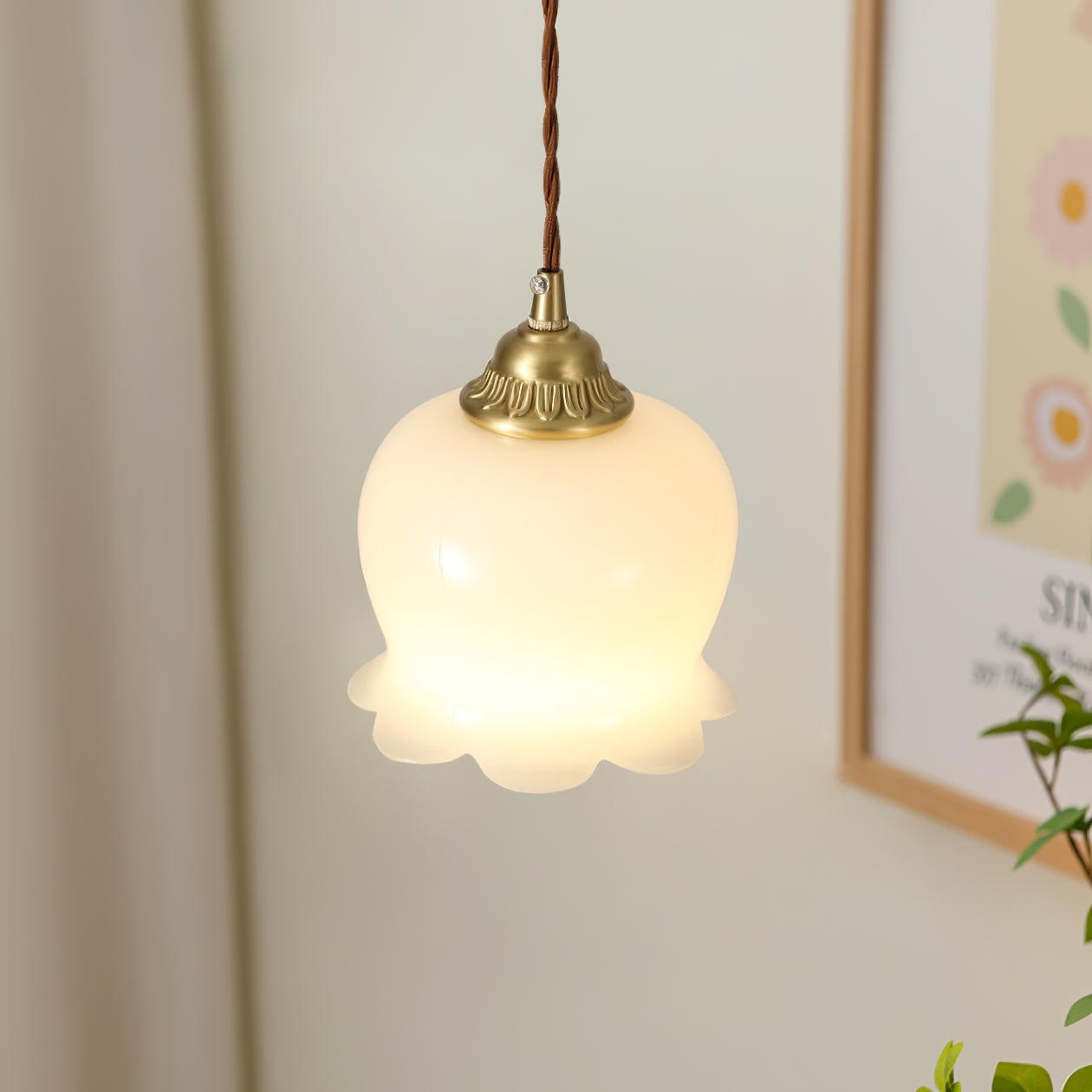 Brass petal pendant light shown close up against a wall
