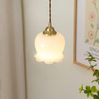 Brass pendant light with beige petal shade glowing gently