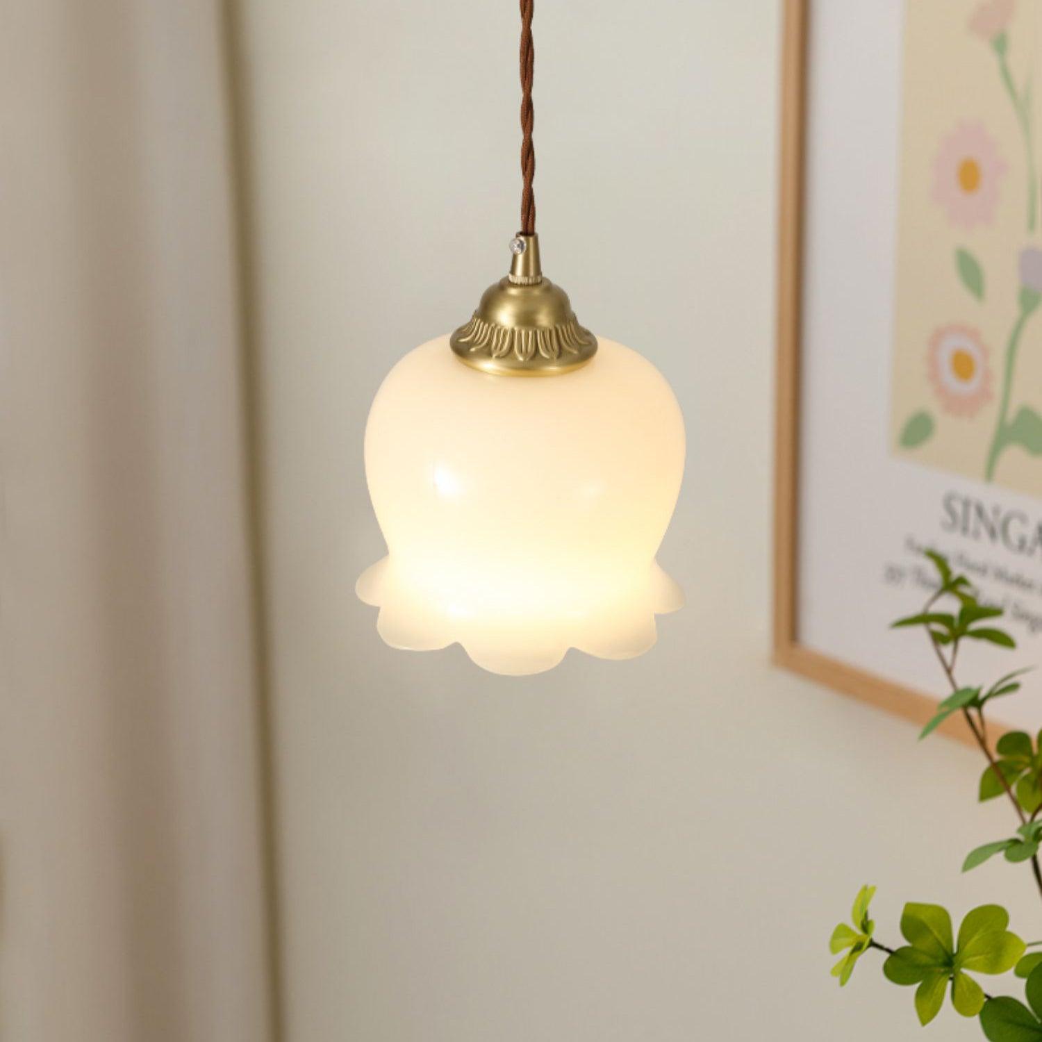 Brass pendant light with beige petal shade glowing gently